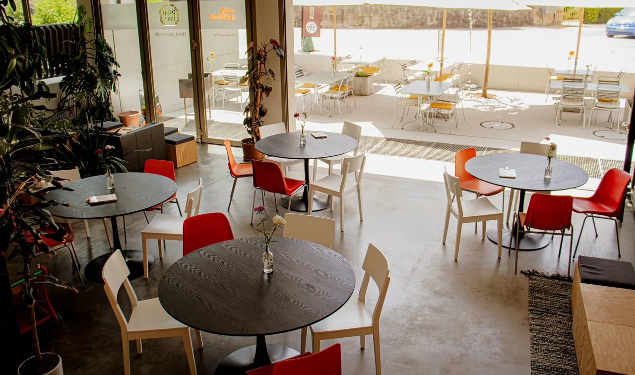 Runde Tische, bunte Stühle und die sonnige Terrasse im Third Place.